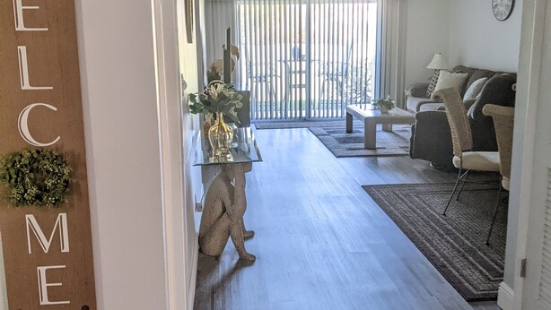 A modern living room with a sofa, a coffee table, and a decorative wall sign. - St. Pete Beach / Isla Del Sol -  2 bedroom 2 bath Condo (St. Petersburg)