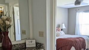 A bedroom with a bed, a nightstand, a lamp, and a window. - St. Pete Beach / Isla Del Sol -  2 bedroom 2 bath Condo (St. Petersburg)