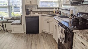 A kitchen with white cabinets, a dishwasher, a stove, and a microwave. - St. Pete Beach / Isla Del Sol -  2 bedroom 2 bath Condo (St. Petersburg)