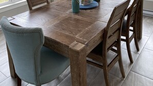 Comedor con mesa de madera, sillas y una araña. Ventanas con vistas a zonas verdes.