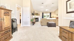 A spacious living room with a fireplace, a sofa, and a wooden cabinet. - Private Pensacola Getaway Minutes to Perdido Key! (Pensacola)