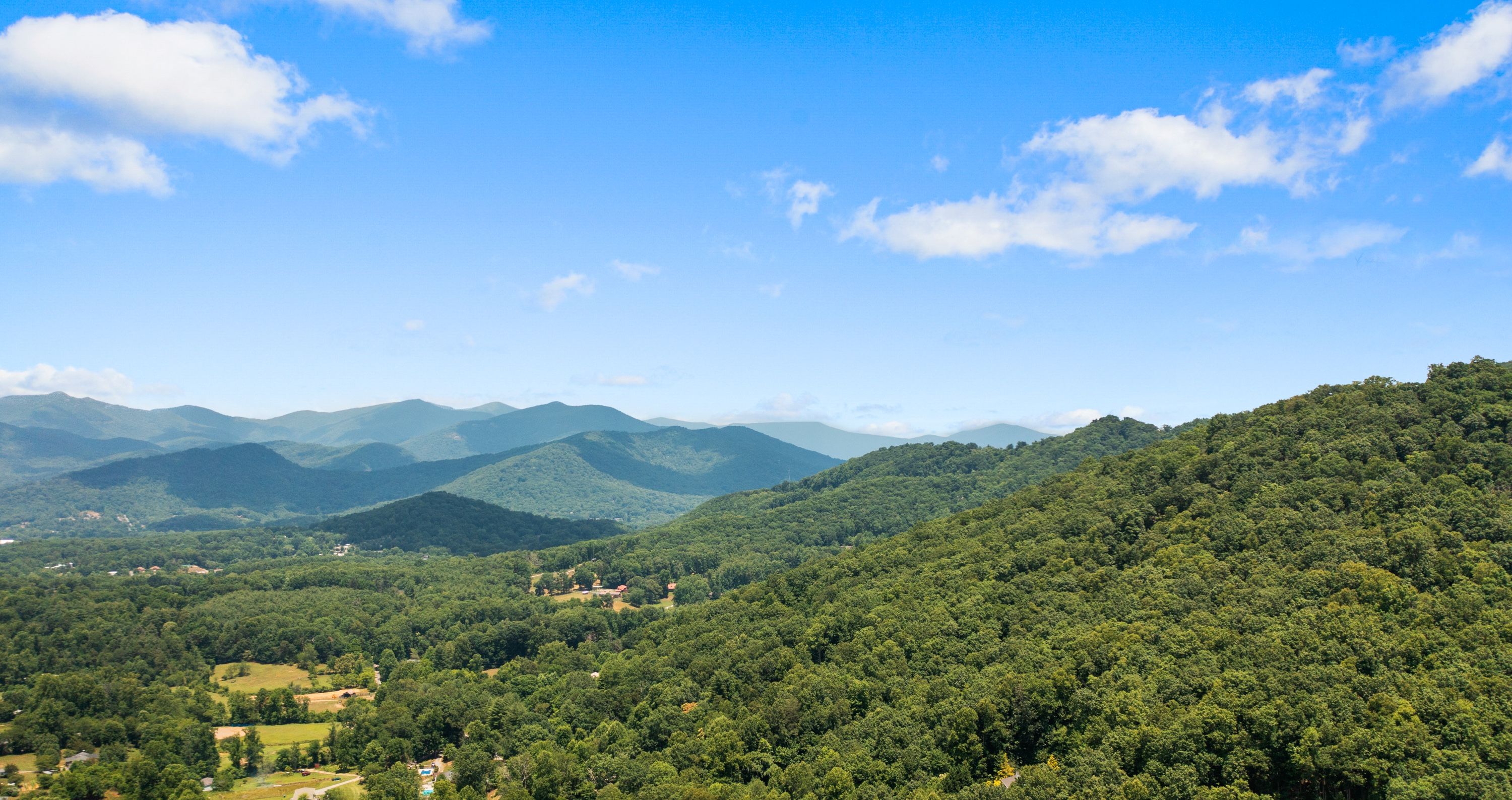 A mountainous landscape with dense forestation and a property marked on the slope.