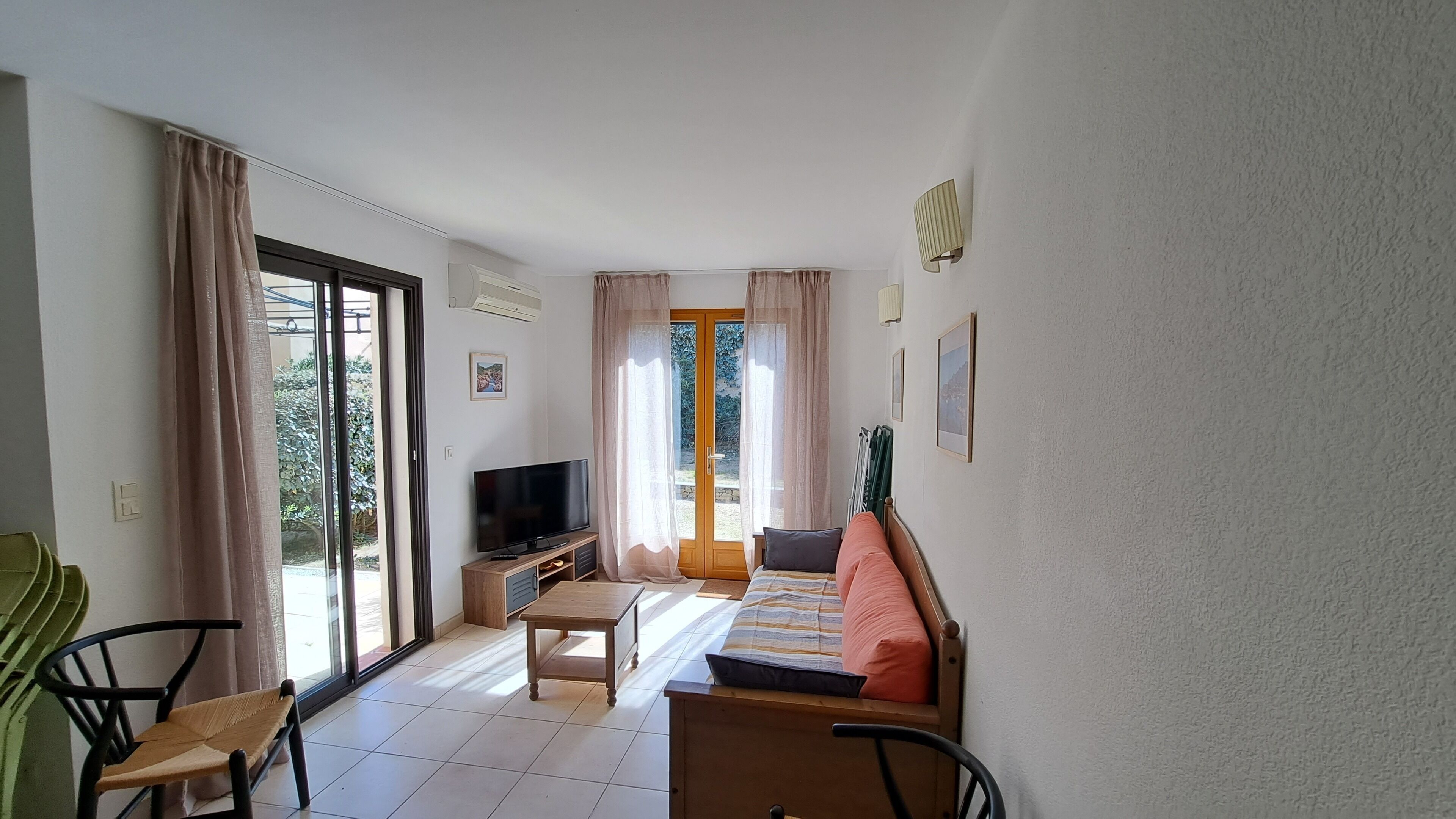 Una stanza con un letto, una TV, un tavolo e una sedia. C'è una porta scorrevole in vetro che dà su una zona esterna.