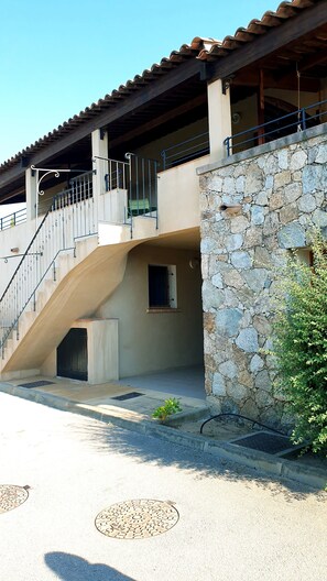 A building with a stone facade, a metal staircase, and a small window.