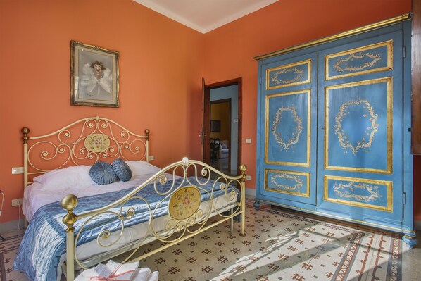 A bedroom with a bed, a wardrobe, and a framed picture on the wall.