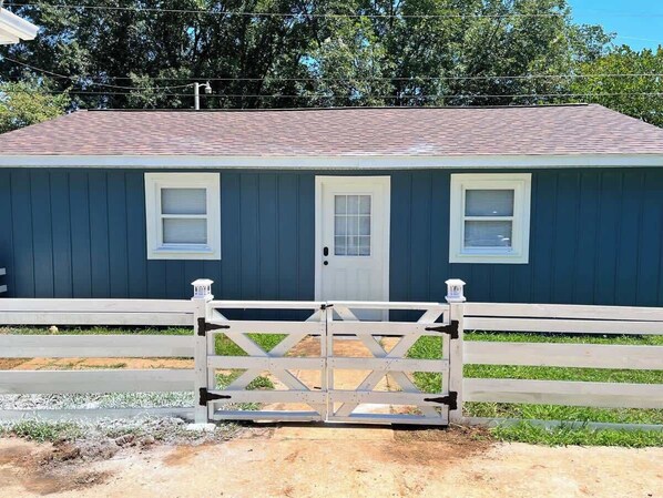 A stable with a closed gate, a single door, and two windows.