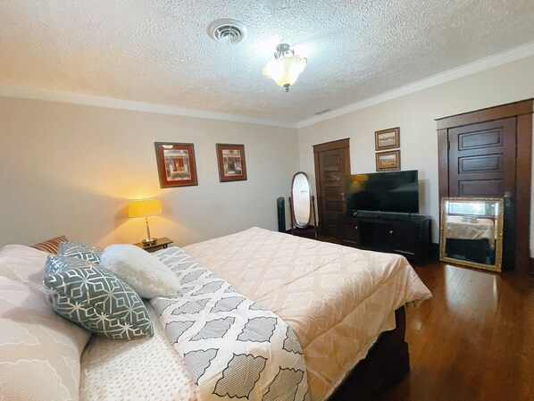 Una habitación de hotel con cama, televisor, espejo y armario.