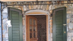 Un bâtiment en pierre doté de deux portes vertes, chacune étant encadrée de métal et comportant une petite fenêtre.