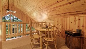 Eine Holzhütte mit Essbereich, Deckenventilator und Blick ins Freie.