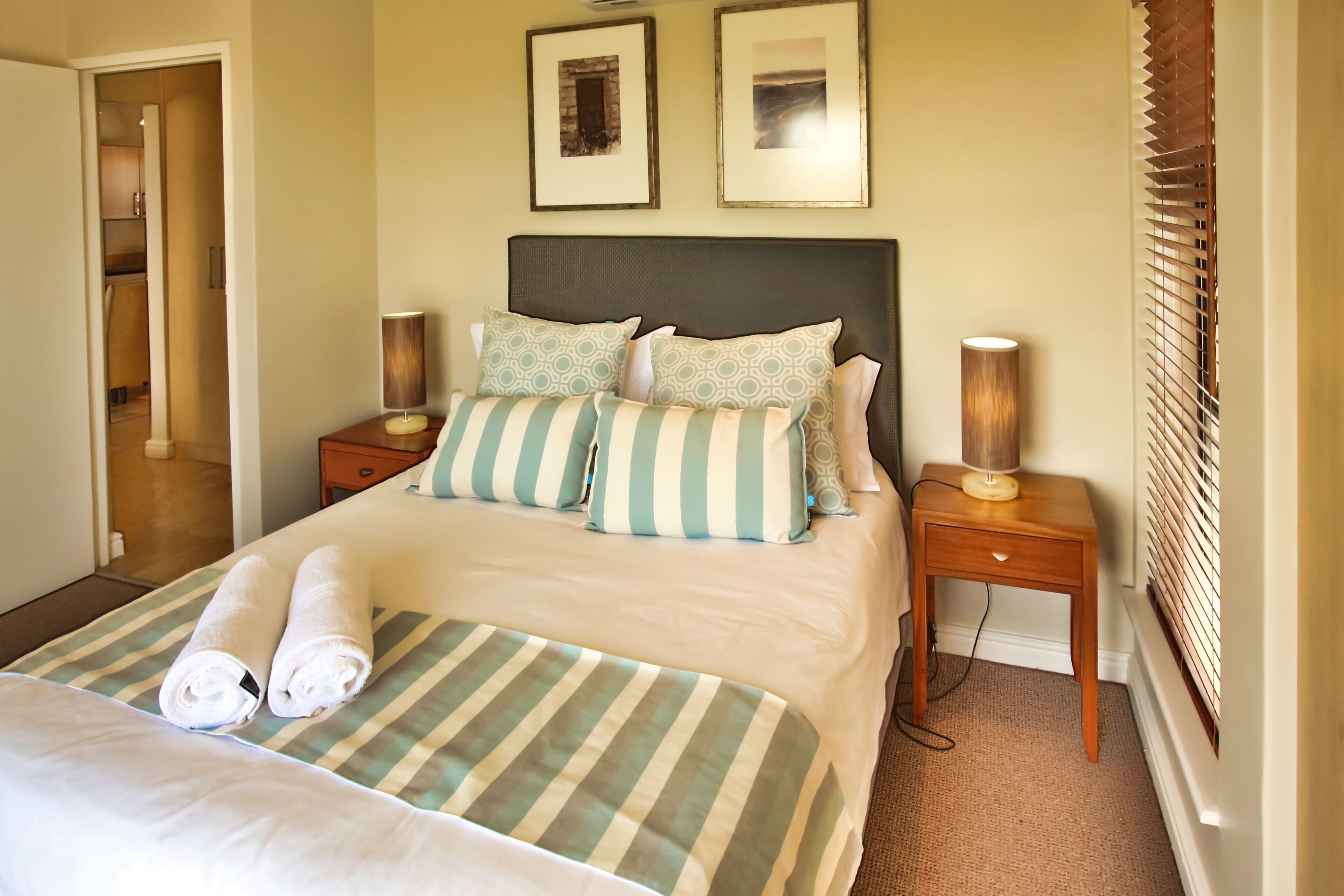 A neatly made bed with striped bedding, two bedside lamps, and a headboard.