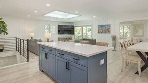 A modern kitchen with a central island, built-in appliances, and a dining area with a table and chairs. - Luxury Beach House - Group/Family/Dog Friendly (Hilton Head Island)