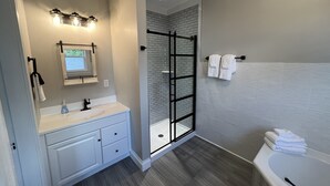 Een moderne badkamer met een douchecabine van glas, een wastafel met spiegel en een bad.
