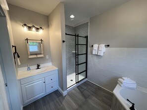 Un baño moderno con cabina de ducha de vidrio, tocador con espejo y bañera.
