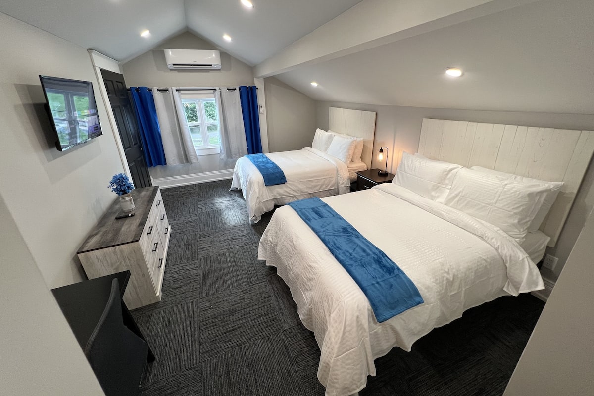 Een hotelkamer met twee bedden, een televisie, een bureau en een raam met gordijnen.
