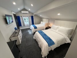 Habitación de hotel con dos camas, televisión, escritorio y ventana con cortinas.