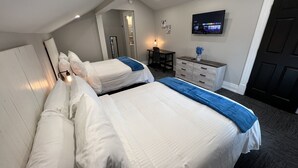 Een hotelkamer met twee bedden, een bureau, een stoel, een kledingkast, een televisie en een deur.