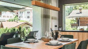 A dining area with a wooden table set for four, surrounded by green upholstered chairs. - 181 Amie Chalet (Santa Cristina Valgardena)