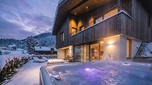 A modern wooden building with a hot tub and outdoor seating area. - 181 Amie Chalet (Santa Cristina Valgardena)