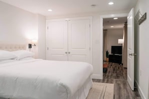 Une chambre à coucher avec un lit double, une armoire blanche et un téléviseur en arrière-plan.
