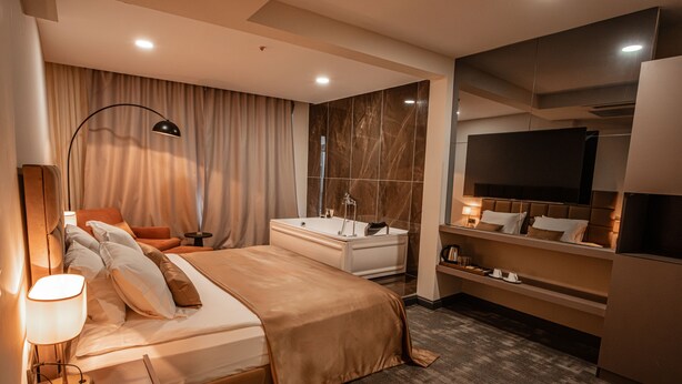 A modern hotel room with a large bed, a desk, a vanity, and a television. - Daric Hotels (Atakum)