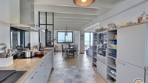 Une cuisine moderne dotée d’un îlot central, d’un coin repas offrant une vue agréable et d’un meuble de rangement orné d’un logo.