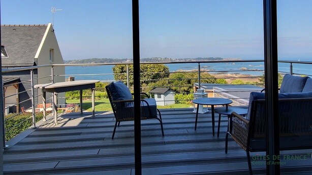 Un balcone con posti a sedere all'aperto, un tavolo e vista sul mare e sulla costa.