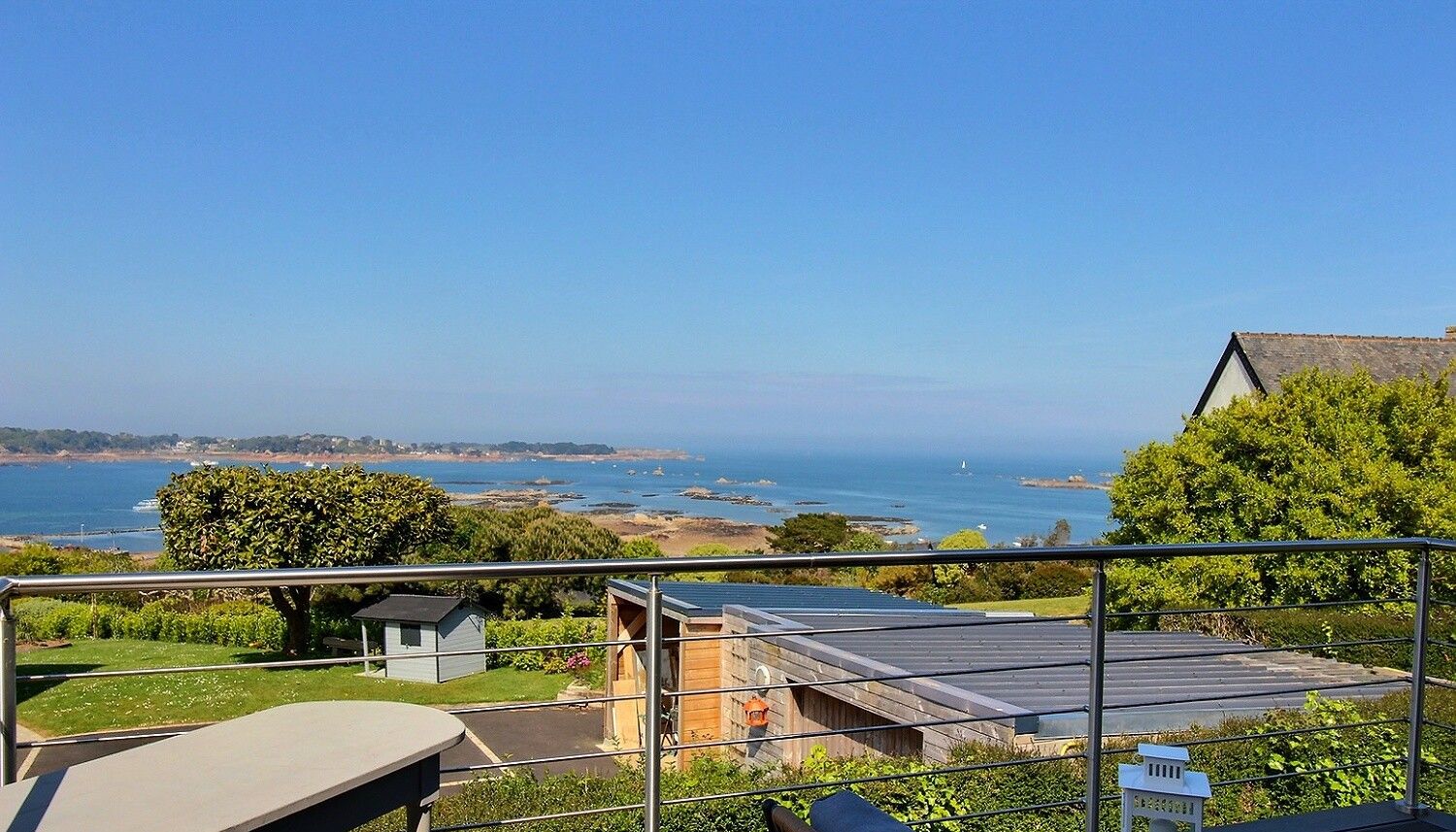 A balcony with a view of the sea, a small shed, and a lamp post.