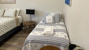 A bedroom with two beds, a bedside table with a lamp, and a framed picture on the wall. - Great One Room with Full Bath Guest House! (Darien)