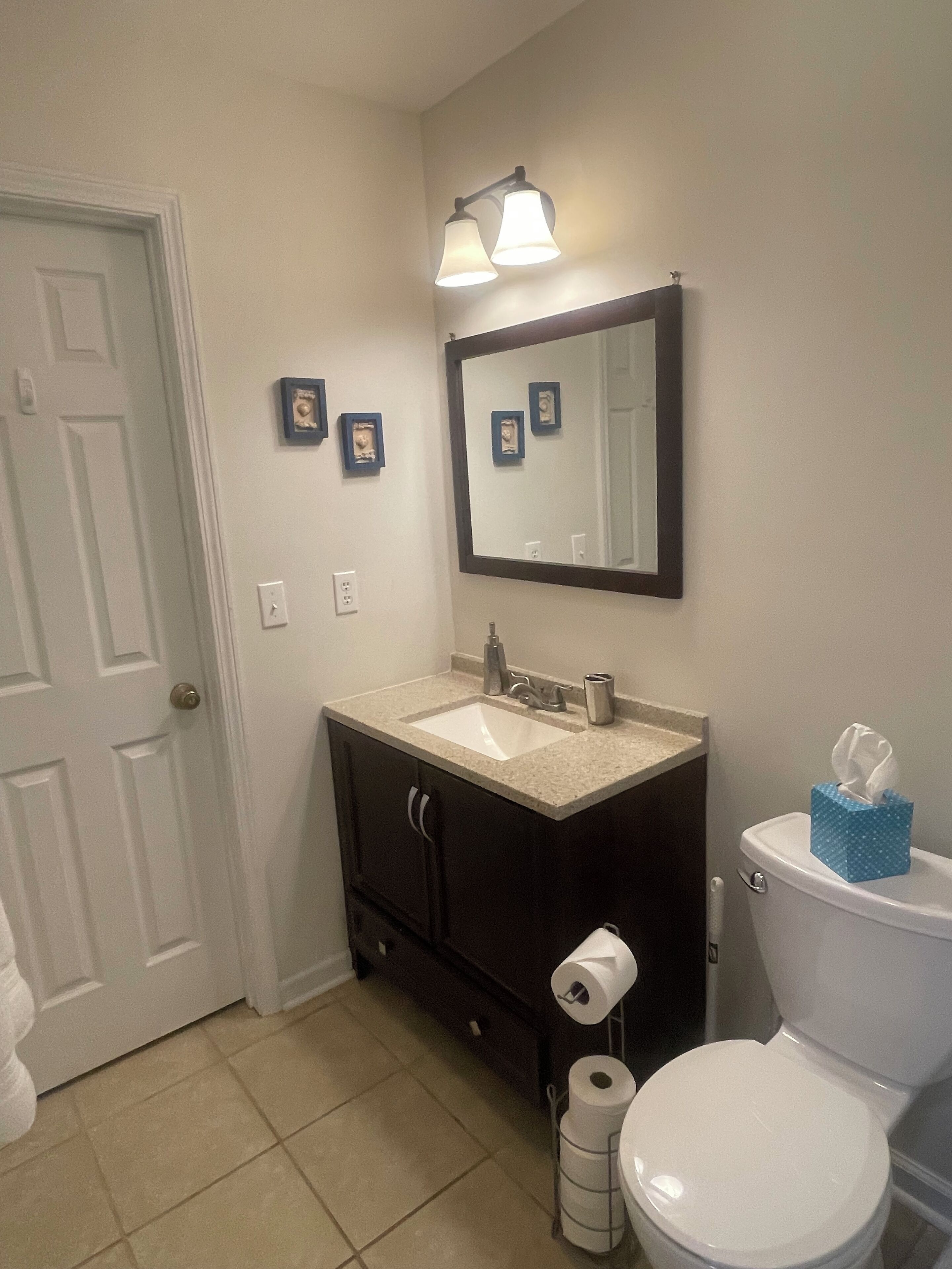 Un baño con un inodoro blanco, un lavabo con un espejo encima y un perchero para toallas.
