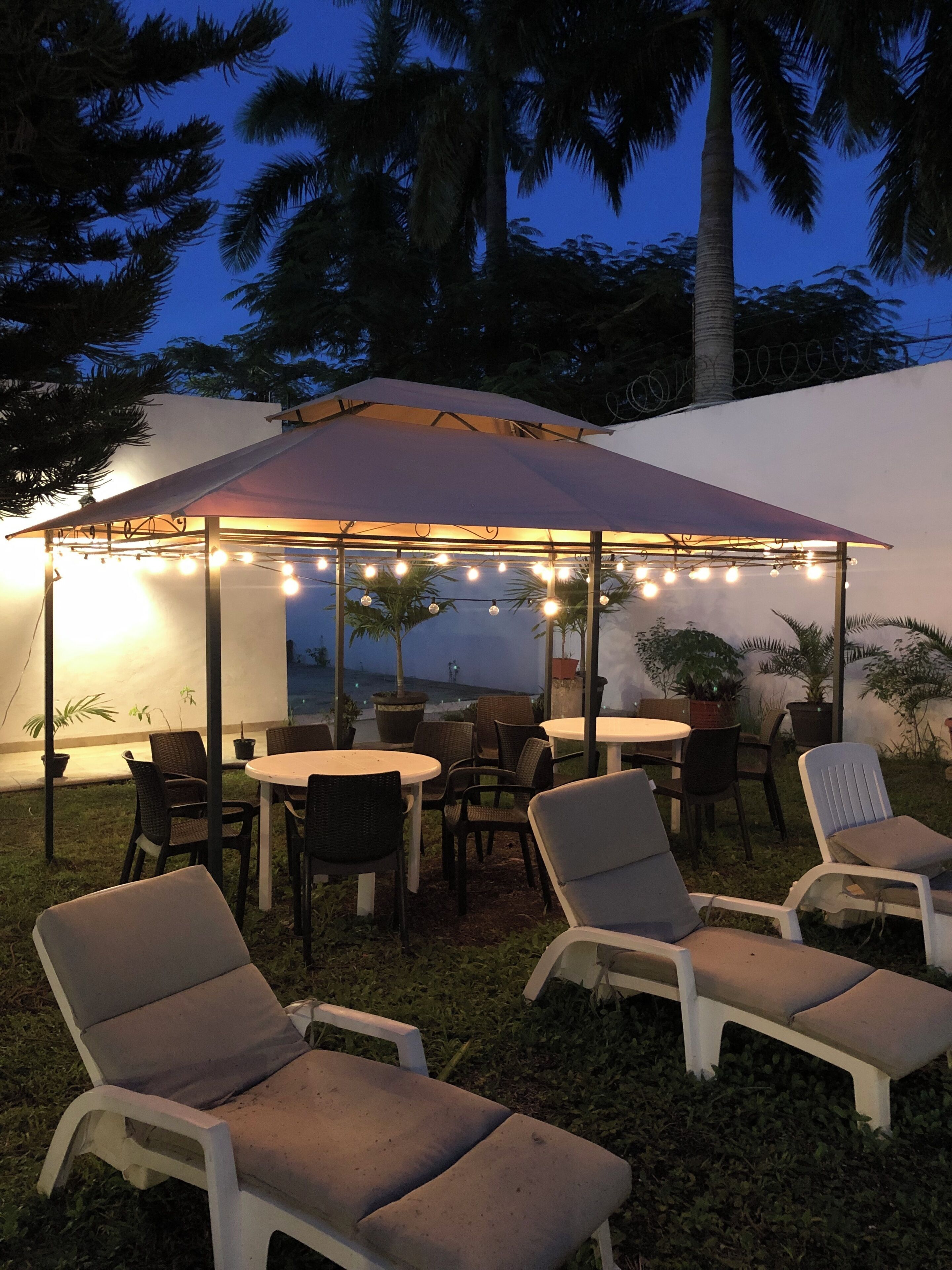 An outdoor patio area with a covered seating area, string lights, and potted plants.