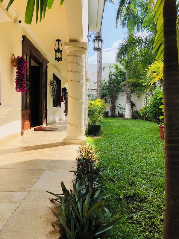 A well-maintained outdoor area with a paved walkway, a grassy lawn, and various potted plants. - Hotel Boutique Villas Segovia Cozumel (Cozumel)