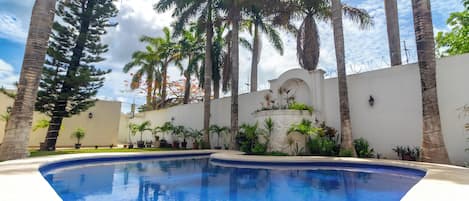 Una piscina al aire libre, sillones reclinables de piscina