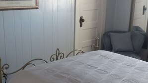 Un dormitorio con cama, una silla y una puerta.