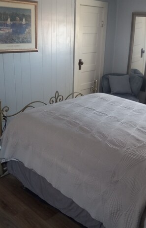 Une chambre à coucher avec un lit, une chaise et une porte.