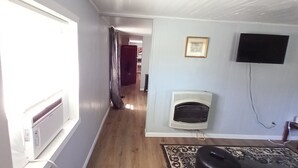 Un pasillo con un radiador, un televisor montado en la pared y un tapete estampado en el suelo.