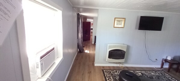 A hallway with a radiator, a television mounted on the wall, and a patterned rug on the floor. - Spend the night in this blast-from-the past 1930's Shot Gun House (Canyon)