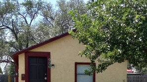 Un edificio pequeño de una sola planta con una puerta roja y un buzón.