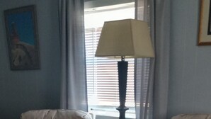 Un salón con dos sofás beige, un otoman negro, una mesita de madera y una lámpara de pie.
