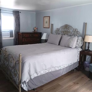 Een slaapkamer met een bed, een dressoir, bedlampen en een raam met gordijnen.