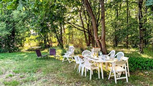 An outdoor dining area with white chairs and a table, surrounded by trees and greenery. - Beautiful home in Selles-sur-Cher with WiFi (Selles-sur-Cher)