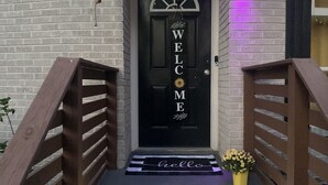 A black door with "WELCOME" written on it, a wooden staircase, and a purple light on the wall. - Family-Friendly Home with Downstairs Suite (Decatur)