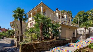 A multi-story building with a balcony, surrounded by palm trees and colorful steps. - 1 bedroom awesome apartment in Lovran (Lovran)