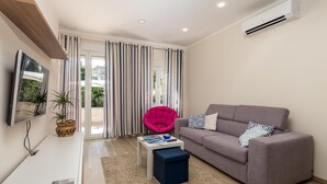 A modern living room with a grey sofa, a small coffee table, a pink chair, and a TV mounted on the wall. - 1 bedroom awesome apartment in Lovran (Lovran)
