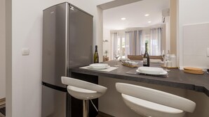 A modern kitchen with a stainless steel refrigerator, two white bar stools, and a dining area with a table set for two. - 1 bedroom awesome apartment in Lovran (Lovran)