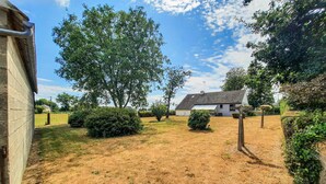 A residential property with a grassy yard, a white house with a tiled roof, and mature trees. - 2 bedroom stunning home in Bacilly (Bacilly)
