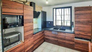 A modern kitchen with wooden cabinets, a Bosch oven, and a window with a view. - 2 bedroom stunning home in Bacilly (Bacilly)