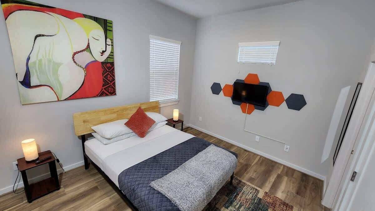 A bedroom with a bed, a nightstand, a wall art piece, and a geometric wall decoration.