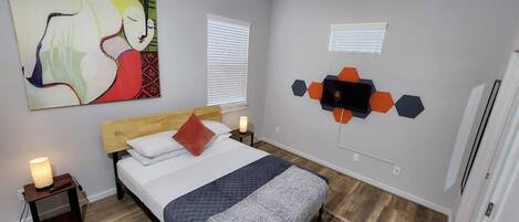 A bedroom with a bed, a nightstand, a wall art piece, and a geometric wall decoration.