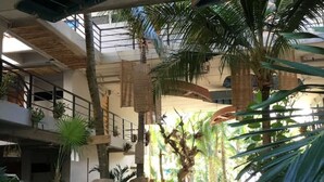 Un atrium interior amb un camí central, palmeres i un cartell que anuncia un esdeveniment de 'Summer Party'.