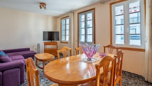 Un coin repas avec une table en bois, des chaises et un téléviseur posé sur un meuble.